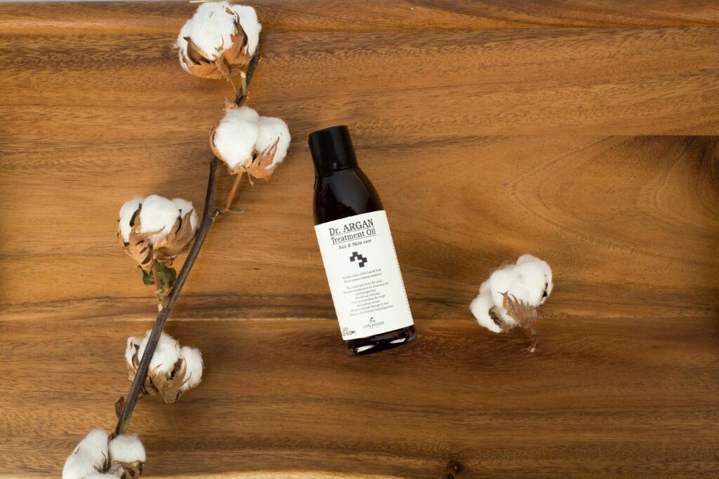 High-quality argan oil bottle on wooden surface with cotton branch. Perfect for natural product ads.